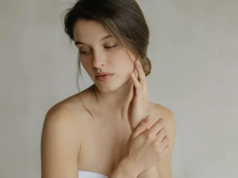 Mujer con la piel luminosa tocándose la mejilla