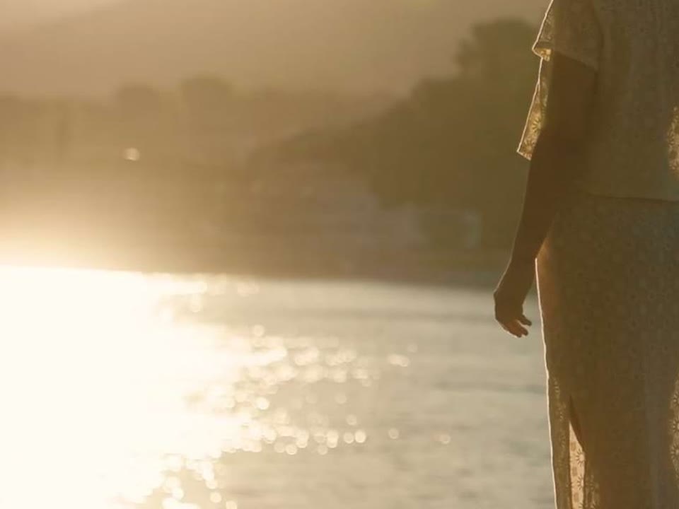 Mujer frente al mar al atardecer
