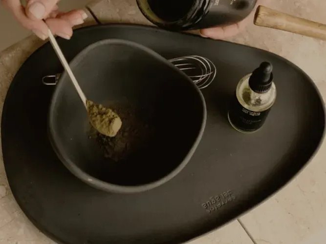 Cuenco con barro en polvo y aceite sobre una bandeja de piedra