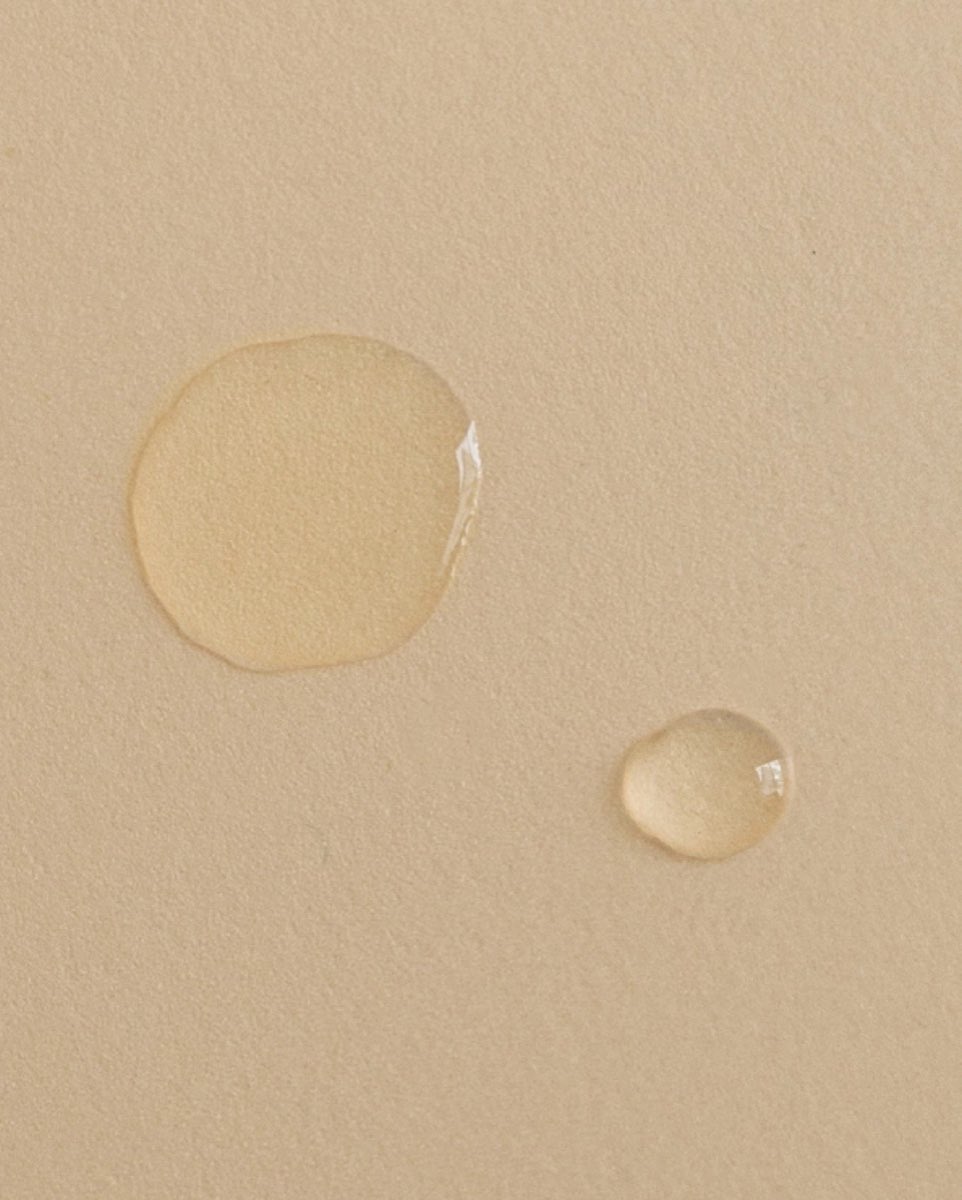Gotas de textura acuosa sobre una superficie color arena